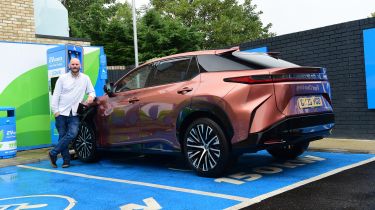 Auto Express creative director Darren Wilson standing with the Lexus RZ in a charging bay